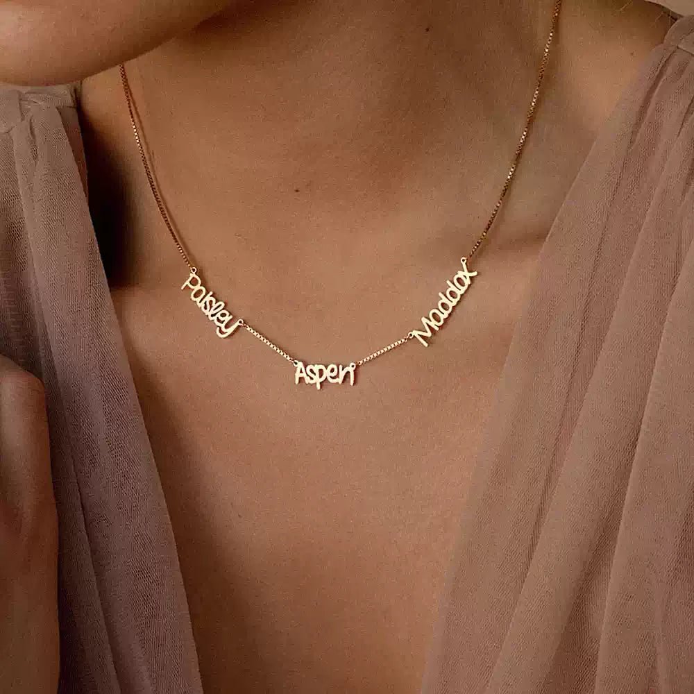Gold necklace with engraved names on a person wearing a sheer top.Name wiht Box Chain