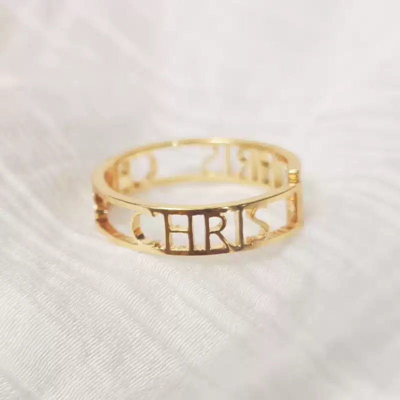 Gold ring with 'CHRIS' engraved on a white fabric background. Stainless Steel Name Jewelry. Custom Gift-Personalized. gift for boyfriend / girlfriend. long-distance relationship gift meaningful keepsake. Memory gift. Christmas couple gift. Birthday Gift. Bold Initial Frame