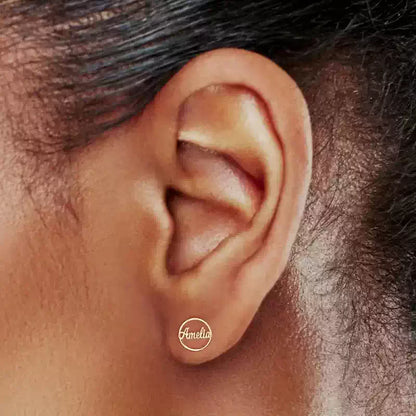 Close-up of an ear with a small circular earring labeled 'Amelia'. Stainless Steel Name Jewelry. Custom Gift-Personalized. gift for boyfriend / girlfriend. long-distance relationship gift meaningful keepsake. Memory gift. Christmas couple gift. Birthday Gift. Circle Charm Name Earrings