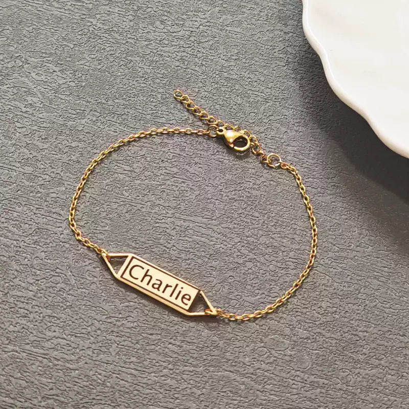 Gold bracelet with 'Charlie' engraving on a gray surface. Hollow Plaque. Stainless Steel Name Jewelry. Custom Gift-Personalized. gift for boyfriend / girlfriend. long-distance relationship gift meaningful keepsake. Memory gift. Christmas couple gift. Birthday Gift. 