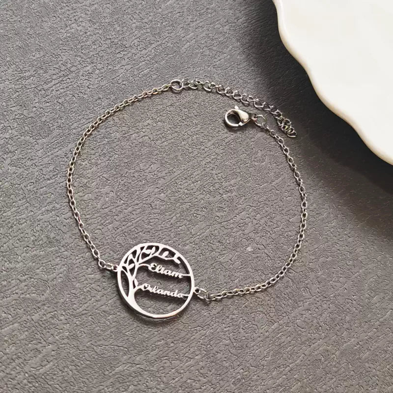 Silver bracelet with tree design and engraved names on a gray surface.  Stainless Steel Name Jewelry. Custom Gift-Personalized. gift for boyfriend / girlfriend. long-distance relationship gift meaningful keepsake. Memory gift. Christmas couple gift. Birthday Gift. 
