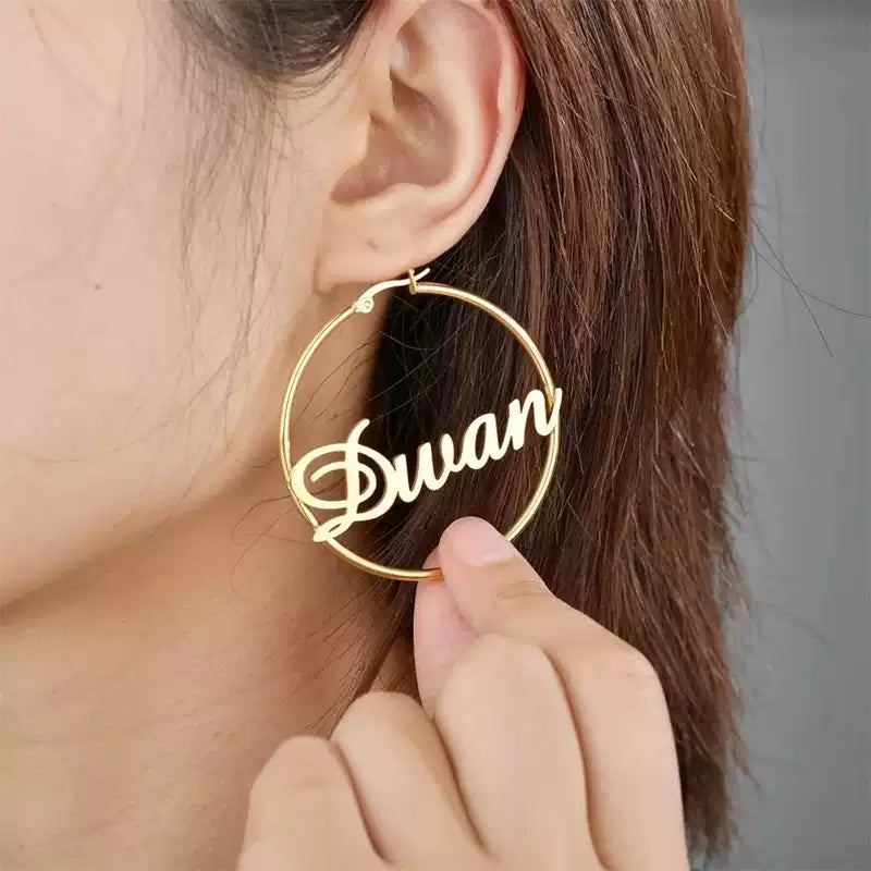 Gold hoop earring with 'Duwan' inscription held near an ear. Stainless Steel Name Jewelry. Custom Gift-Personalized. gift for boyfriend / girlfriend. long-distance relationship gift meaningful keepsake. Memory gift. Christmas couple gift. Birthday Gift. Retro Classic Hoop Name Earrings