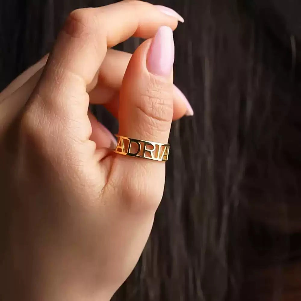 Gold ring with 'ADRIAN' on a person's finger against a dark background. Stainless Steel Name Jewelry. Custom Gift-Personalized. gift for boyfriend / girlfriend. long-distance relationship gift meaningful keepsake. Memory gift. Christmas couple gift. Birthday Gift. Bold Initial Frame. 