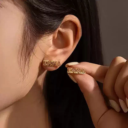 Gold earrings with 'EMMA' text held by a hand against a neutral background Stainless Steel Name Jewelry. Custom Gift-Personalized. gift for boyfriend / girlfriend. long-distance relationship gift meaningful keepsake. Memory gift. Christmas couple gift. Birthday Gift. Hollow Line Name Studs