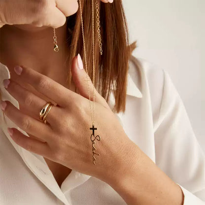 Person wearing a gold necklace with a cross pendant and 'Faith' inscription, holding it near their face.. Stainless Steel Name Jewelry. Custom Gift-Personalized. gift for boyfriend / girlfriend. long-distance relationship gift meaningful keepsake. Memory gift. Christmas couple gift. Birthday Gift. Cross Name Necklace
