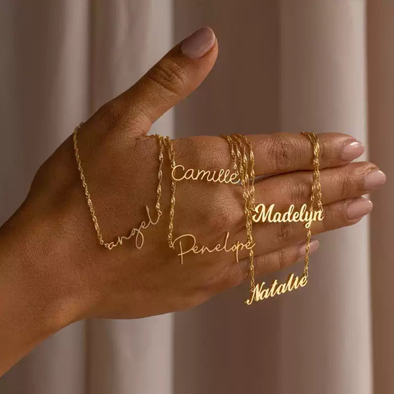 Hand wearing gold name necklaces with a soft background. Stainless Steel Name Jewelry. Custom Gift-Personalized. gift for boyfriend / girlfriend. long-distance relationship gift meaningful keepsake. Memory gift. Christmas couple gift. Birthday Gift. Wave Chain Name Necklace