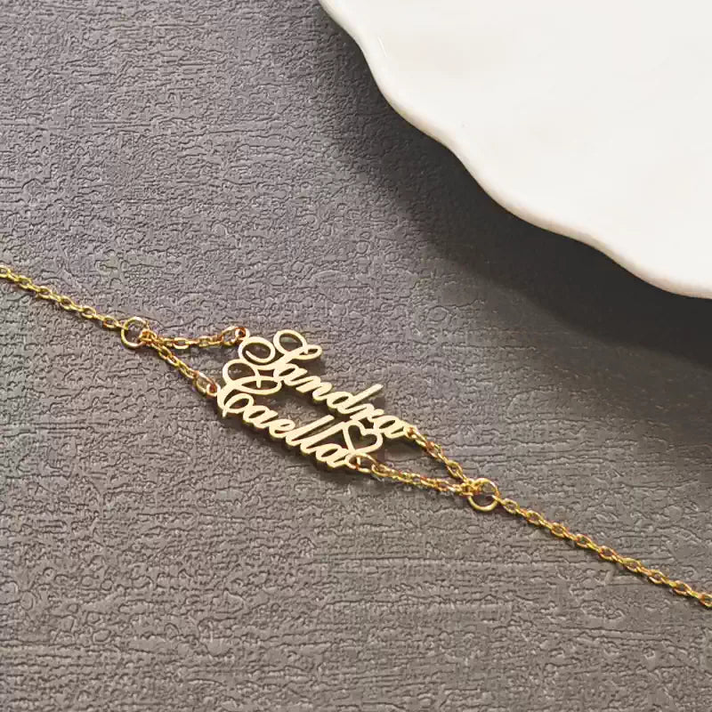 Gold name necklace on a textured gray surface. Double Name Layered. Stainless Steel Name Jewelry. Custom Gift-Personalized. gift for boyfriend / girlfriend. long-distance relationship gift meaningful keepsake. Memory gift. Christmas couple gift. Birthday Gift. 