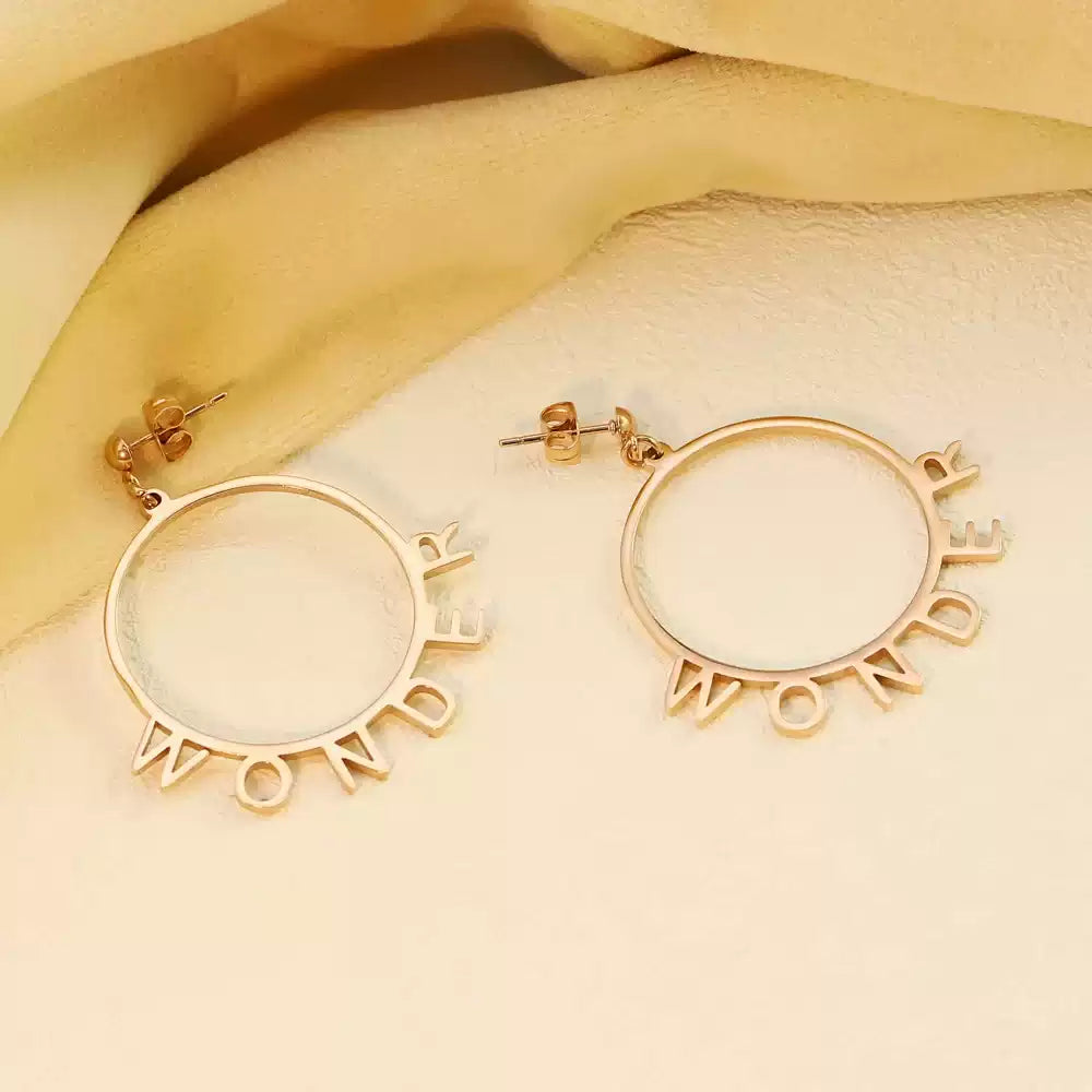 Gold hoop earrings with 'WONDER' text on a beige fabric background Stainless Steel Name Jewelry. Custom Gift-Personalized. gift for boyfriend / girlfriend. long-distance relationship gift meaningful keepsake. Memory gift. Christmas couple gift. Birthday Gift. Playful Circle Name Earrings