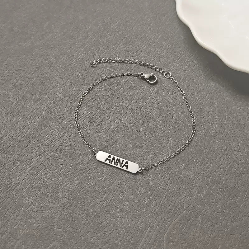 Silver bracelet with 'ANNA' engraving on a gray surface. Hollow Plaque. Stainless Steel Name Jewelry. Custom Gift-Personalized. gift for boyfriend / girlfriend. long-distance relationship gift meaningful keepsake. Memory gift. Christmas couple gift. Birthday Gift. 