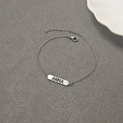 Silver bracelet with 'ANNA' engraving on a gray surface. Hollow Plaque. Stainless Steel Name Jewelry. Custom Gift-Personalized. gift for boyfriend / girlfriend. long-distance relationship gift meaningful keepsake. Memory gift. Christmas couple gift. Birthday Gift. 