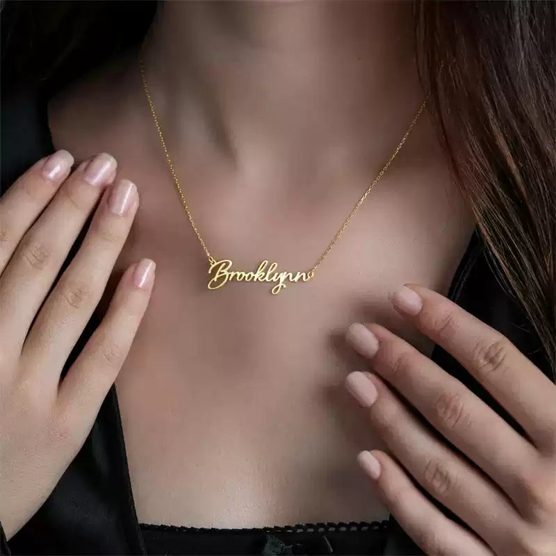 Gold 'Brooklyn' necklace on a person's neck with hands adjusting it. Stainless Steel Name Jewelry. Custom Gift-Personalized. gift for boyfriend / girlfriend. long-distance relationship gift meaningful keepsake. Memory gift. Christmas couple gift. Birthday Gift. Classic Name Necklace (Circle Chain)