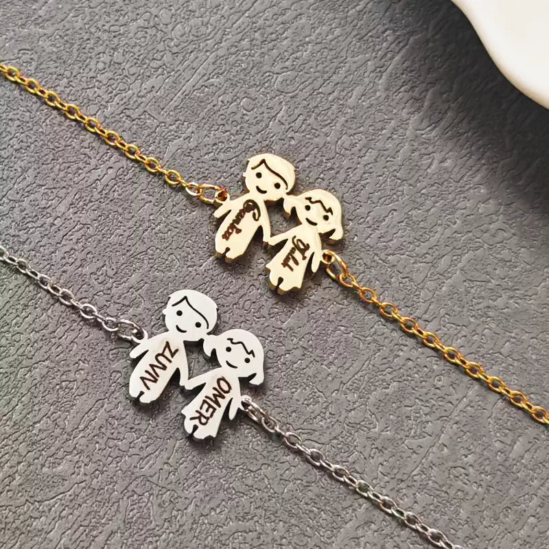 Two gold and silver necklaces with stick figure pendants on a textured surface. Boy & Girl holding hands. Stainless Steel Name Jewelry. Custom Gift-Personalized. gift for boyfriend / girlfriend. long-distance relationship gift meaningful keepsake. Memory gift. Christmas couple gift. Birthday Gift. 