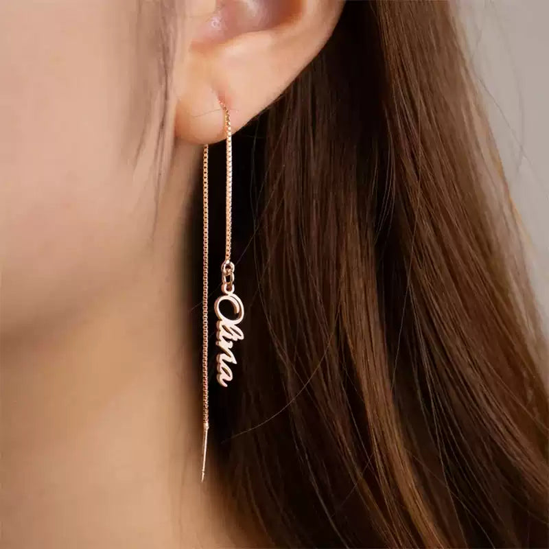 Gold name thread earrings worn by a person with long brown hair. Stainless Steel Name Jewelry. Custom Gift-Personalized. gift for boyfriend / girlfriend. long-distance relationship gift meaningful keepsake. Memory gift. Christmas couple gift. Birthday Gift. Vertical Chain Threader Earrings