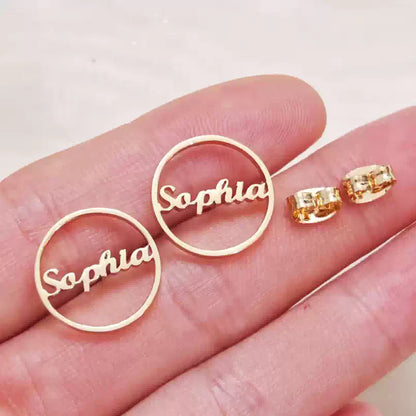 Gold 'Sophia' earrings on a hand against a light background Stainless Steel Name Jewelry. Custom Gift-Personalized. gift for boyfriend / girlfriend. long-distance relationship gift meaningful keepsake. Memory gift. Christmas couple gift. Birthday Gift. Circle Charm Name Earrings