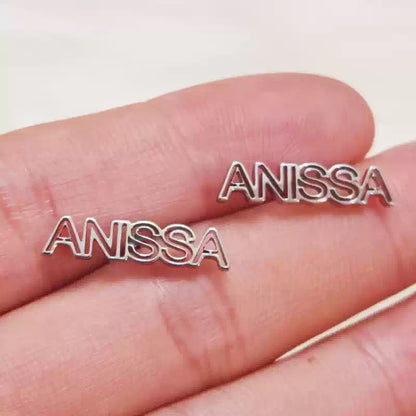 Silver 'ANISSA' nameplate held between fingers on a white background Stainless Steel Name Jewelry. Custom Gift-Personalized. gift for boyfriend / girlfriend. long-distance relationship gift meaningful keepsake. Memory gift. Christmas couple gift. Birthday Gift. Hollow Line Name Studs