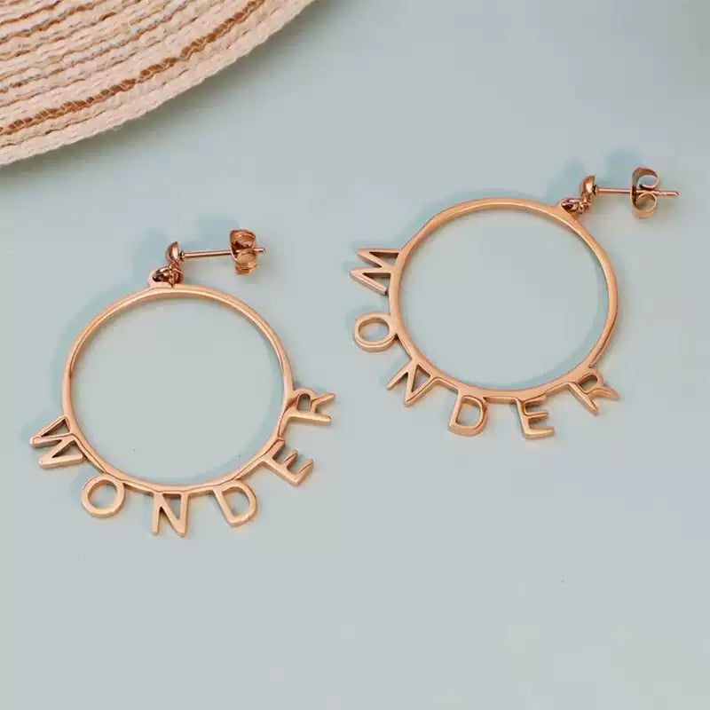 Rose gold hoop earrings with 'WONDER' inscription on a light blue background Stainless Steel Name Jewelry. Custom Gift-Personalized. gift for boyfriend / girlfriend. long-distance relationship gift meaningful keepsake. Memory gift. Christmas couple gift. Birthday Gift. Playful Circle Name Earrings