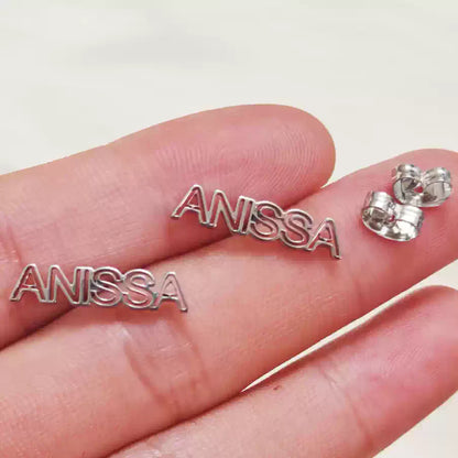 Silver 'ANISSA' earrings held between fingers on a light background Stainless Steel Name Jewelry. Custom Gift-Personalized. gift for boyfriend / girlfriend. long-distance relationship gift meaningful keepsake. Memory gift. Christmas couple gift. Birthday Gift. Hollow Line Name Studs