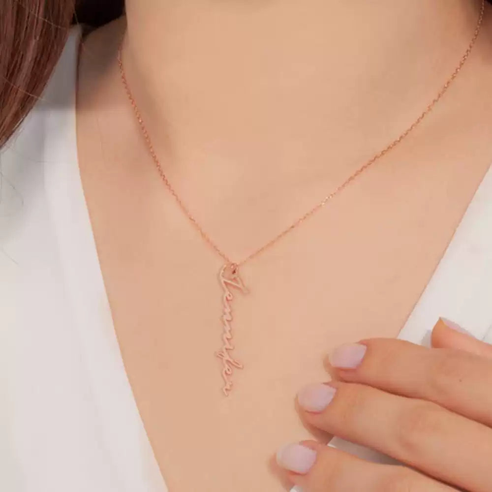 Rose gold necklace with a delicate pendant on a person wearing a white top. Stainless Steel Name Jewelry. Custom Gift-Personalized. gift for boyfriend / girlfriend. long-distance relationship gift meaningful keepsake. Memory gift. Christmas couple gift. Birthday Gift. Vertical Name Necklace