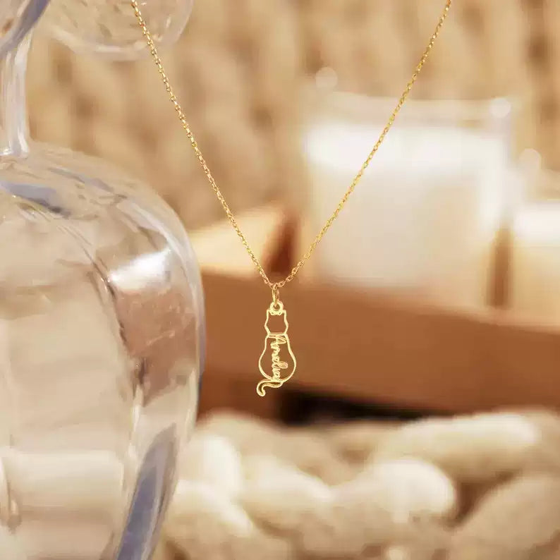 Gold necklace with a light bulb pendant on a blurred background. Baby Cat Necklace. 