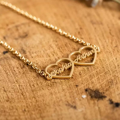 Gold necklace with heart-shaped name pendants on a wooden surface. Double heart. Stainless Steel Name Jewelry. Custom Gift-Personalized. gift for boyfriend / girlfriend. long-distance relationship gift meaningful keepsake. Memory gift. Christmas couple gift. Birthday Gift. 
