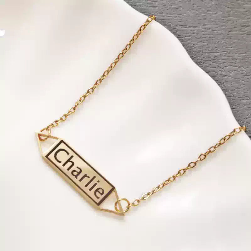 Gold necklace with a nameplate on a white surface. Hollow Plaque. Stainless Steel Name Jewelry. Custom Gift-Personalized. gift for boyfriend / girlfriend. long-distance relationship gift meaningful keepsake. Memory gift. Christmas couple gift. Birthday Gift. 
