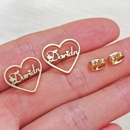 Gold heart-shaped earrings with 'Darlin' on a hand against a white background Stainless Steel Name Jewelry. Custom Gift-Personalized. gift for boyfriend / girlfriend. long-distance relationship gift meaningful keepsake. Memory gift. Christmas couple gift. Birthday Gift. Heart Embrace Name Studs 