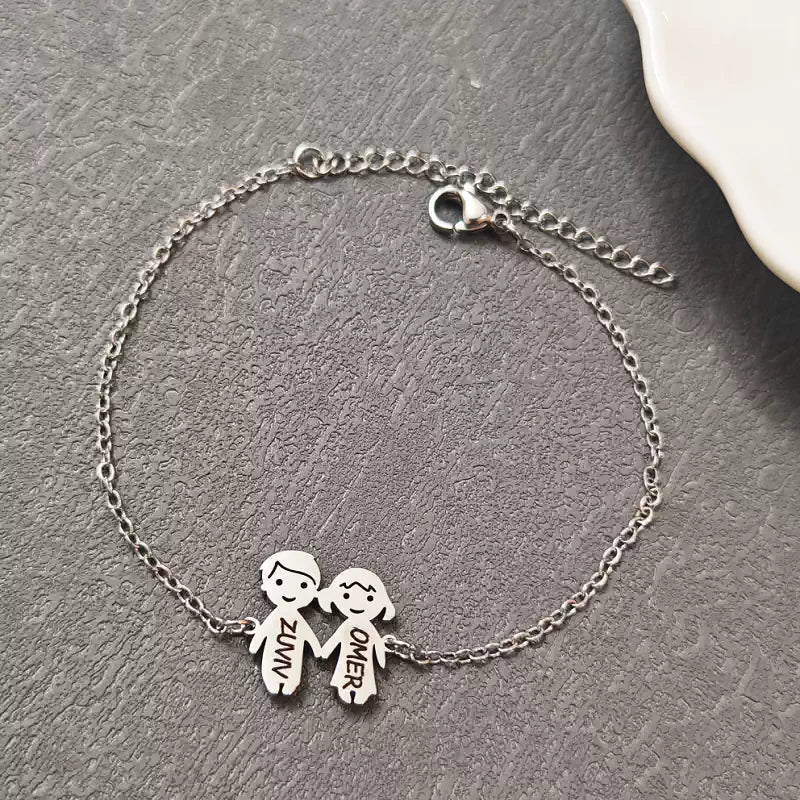 Silver bracelet with two child charms on a gray surface. Boy & Girl holding hands. Stainless Steel Name Jewelry. Custom Gift-Personalized. gift for boyfriend / girlfriend. long-distance relationship gift meaningful keepsake. Memory gift. Christmas couple gift. Birthday Gift. 
