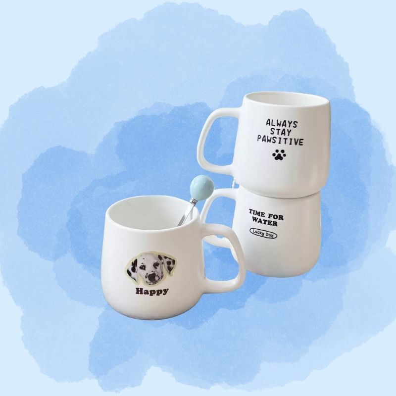 Two white mugs with dog-themed text and graphics on a blue floral background