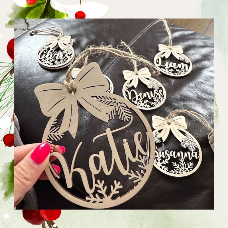 Decorative Christmas ornament with names 'Katie', 'Denise', and 'Susanna' on a dark surface.