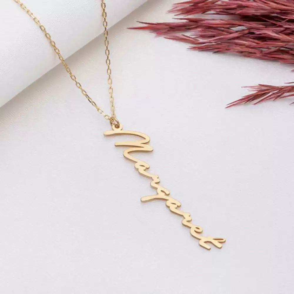 Gold name necklace on a white surface with dried flowers Stainless Steel Name Jewelry. Custom Gift-Personalized. gift for boyfriend / girlfriend. long-distance relationship gift meaningful keepsake. Memory gift. Christmas couple gift. Birthday Gift. Vertical Name Necklace