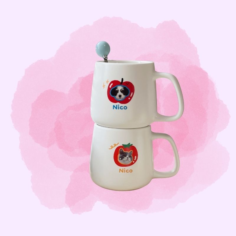 Two stacked ceramic mugs with dog illustrations and 'Nico' text on a pink watercolor background