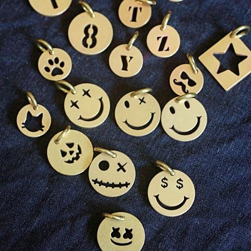 Collection of gold charms with various designs on a dark blue fabric background