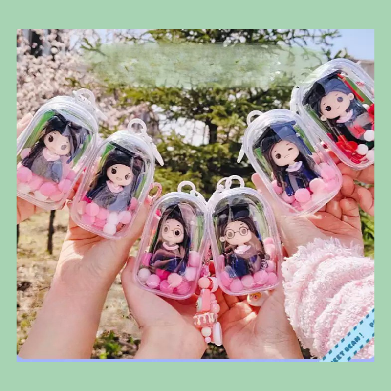 Keychains with cartoon character figures held by hands against a blurred outdoor background. Personalized couple present. Gift for boyfriend girlfriend. Custom-made. Personalized. Perfect gift idea. Meaningful keepsake. Wedding gift. Anniversary gift. Birthday gift